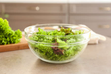 Glass bowl of fresh lettuce on table in kitchen