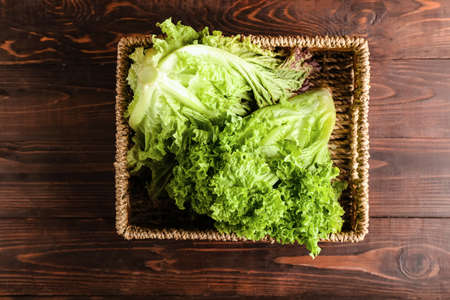 Basket with fresh lettuce on wooden backgroundの写真素材