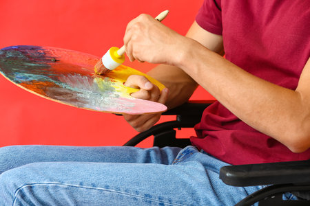 Young male artist in wheelchair against color background, closeupの写真素材