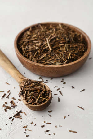 Bowl and spoon with dry hojicha green tea on light backgroundの写真素材