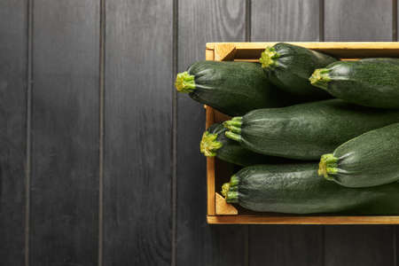 Wooden box with fresh zucchini squashes on dark wooden backgroundの写真素材