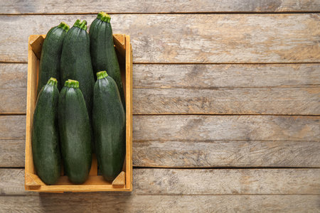 Wooden box with fresh zucchini squashes on wooden backgroundの写真素材