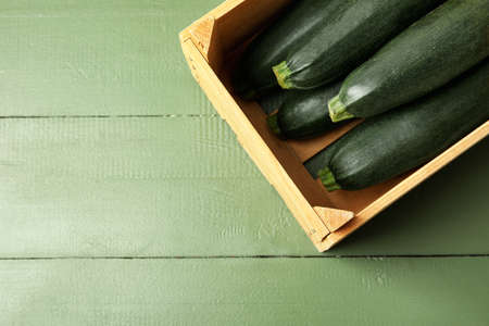 Wooden box with fresh zucchini squashes on color wooden backgroundの写真素材