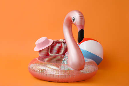 Inflatable ring and beach accessories on color background