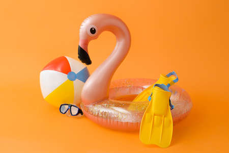 Inflatable ring, ball, snorkeling mask and flippers on color background