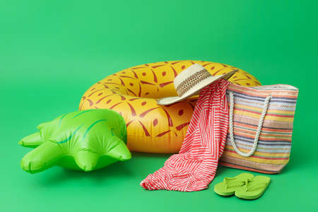 Inflatable ring and beach accessories on color background