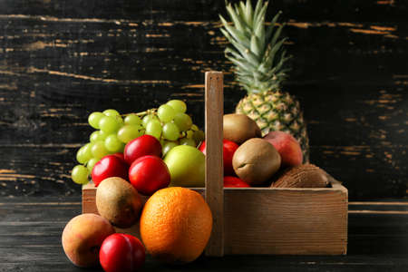 Basket with fresh fruits on dark wooden background