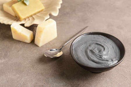 Bowl of activated carbon facial mask, spoon and soap on grunge backgroundの写真素材