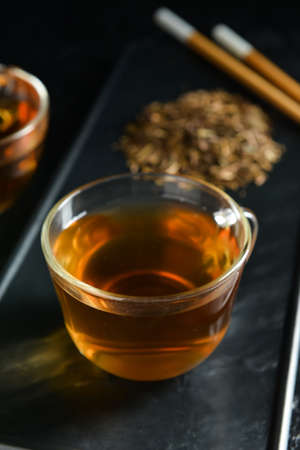 Glass cup of tasty hojicha green tea on black backgroundの写真素材