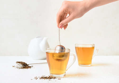 Woman preparing tasty hojicha green tea on white backgroundの写真素材