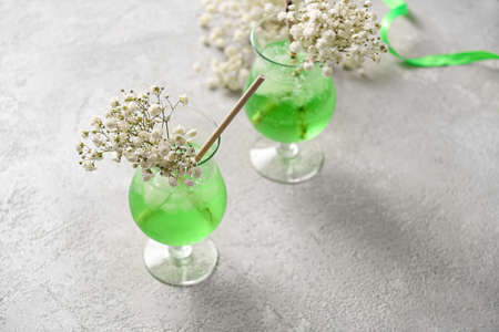 Glasses with tasty cocktail and beautiful gypsophila flowers on light backgroundの写真素材