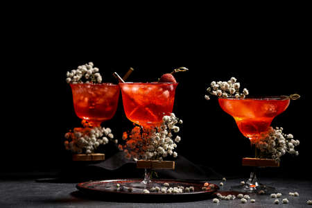 Glasses with tasty cocktail and beautiful gypsophila flowers on dark background