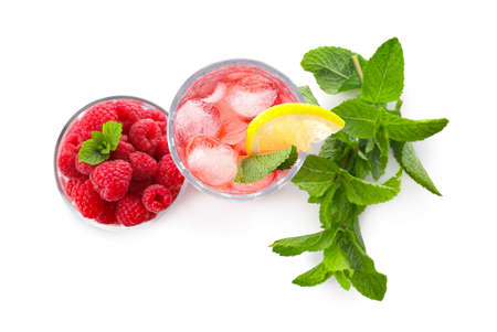 Glass of tasty lemonade and bowl with raspberry on white background