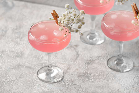 Glasses with tasty cocktail and beautiful gypsophila flowers on light backgroundの写真素材