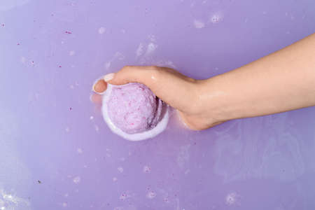 Female hand with dissolving bath bomb in water, closeupの写真素材