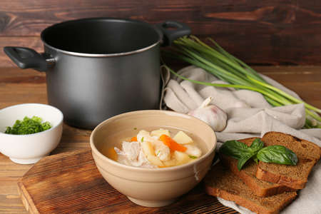 Bowl of delicious dumpling soup and ingredients on wooden table