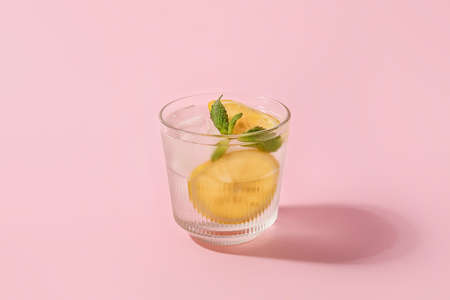 Glass of cold gin and tonic on color background