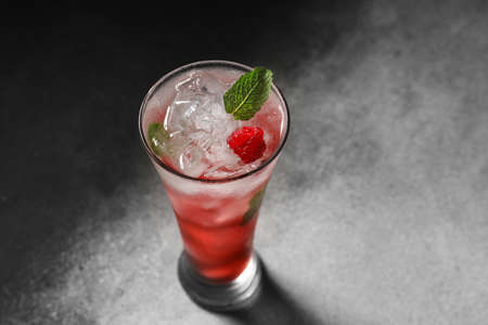 Glass of delicious raspberry lemonade on dark background