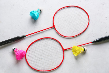 Badminton rackets and shuttlecocks on light background