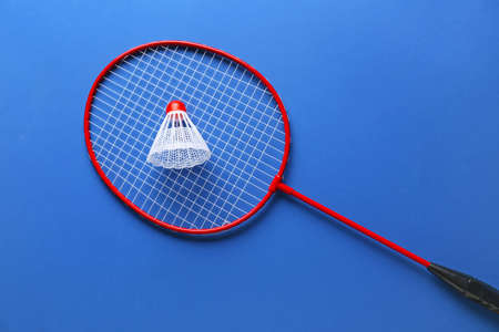 Badminton racket and shuttlecock on color background