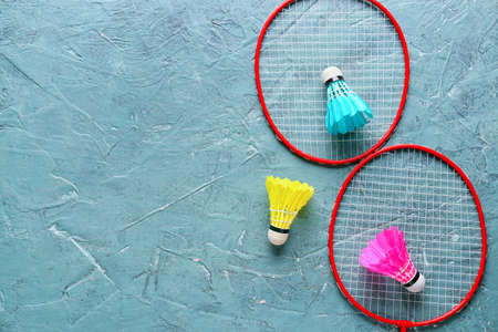 Badminton rackets and shuttlecocks on color background