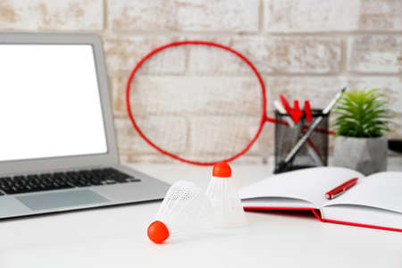 Laptop, badminton racket and shuttlecocks on table in officeの写真素材
