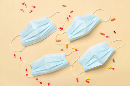 Medical masks and capsules on light background