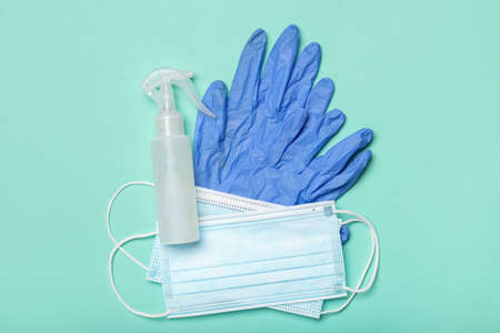 Medical masks, rubber gloves and hand sanitizers on color background