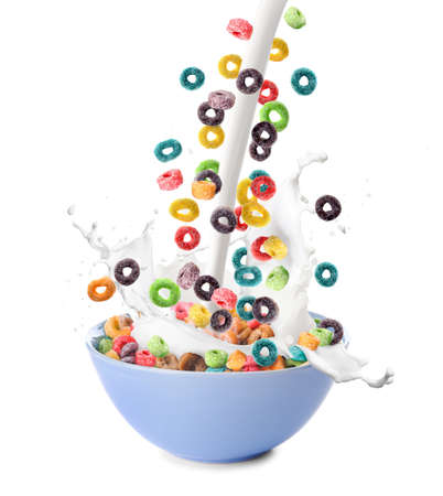 Pouring of tasty corn rings and milk into bowl on white background
