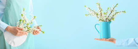 Woman with beautiful blooming spring branches on blue background with space for textの写真素材