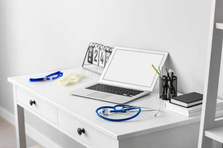 Doctor's workplace with laptop near light wall in medical office