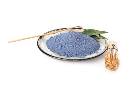 Plate of powdered blue matcha, chasen and chashaku tea on white backgroundの写真素材