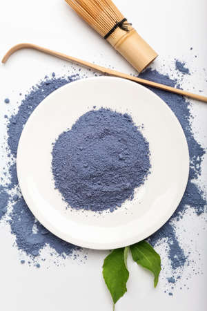 Plate of powdered blue matcha tea, chasen and chashaku on white backgroundの写真素材