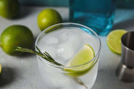 Glass of cold gin tonic on gray background