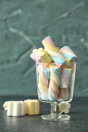 Glass with tasty marshmallows on color background
