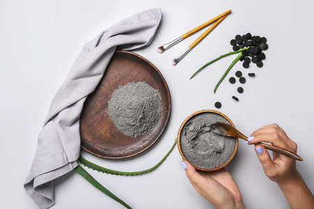 Woman preparing activated carbon facial mask on white backgroundの写真素材