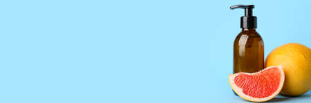 Bottle of essential oil and grapefruits on light blue background with space for textの写真素材