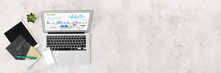 Business statistics on screen of modern laptop, mobile phone, tablet computer and office stationery on grunge background with space for textの写真素材