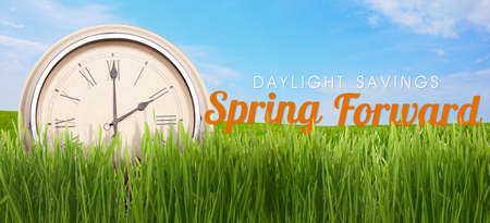 Clock in green grass on spring day outdoors. daylight saving timeの写真素材