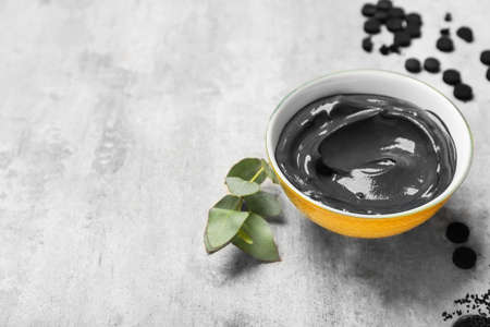 Bowl of activated carbon facial mask on light background, closeupの写真素材