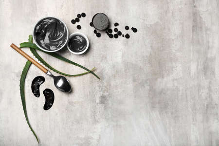 Composition with bowls of activated carbon facial mask, ingredients and under-eye patches on grunge backgroundの写真素材