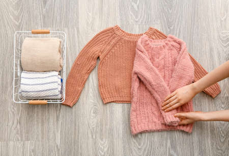 Woman folding clothes on gray wooden background