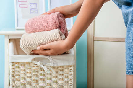 Woman clean clothes into wicker basket putting at home, closeupの写真素材