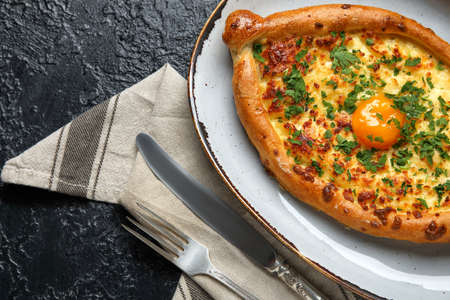 Plate with tasty Ajarian khachapuri on dark background, closeupの写真素材