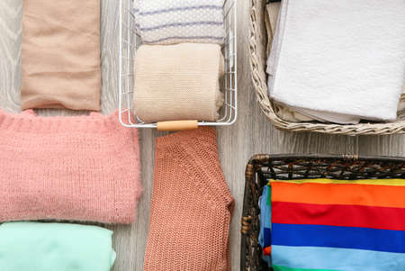 Different baskets and clean clothes on gray background, closeup