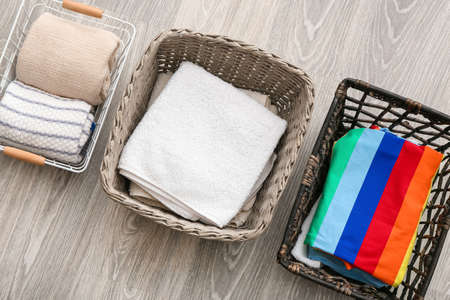 Baskets with clean clothes and towels on gray wooden background, closeupの写真素材