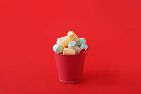Bucket with marshmallows on red background