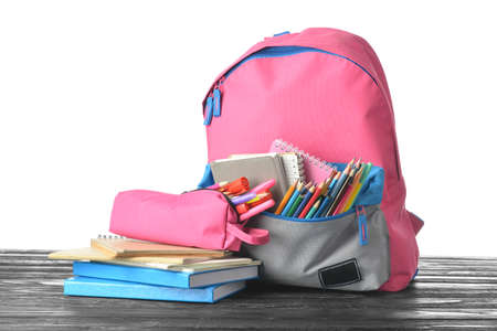 School backpack and stationery on wooden table against white backgroundの写真素材