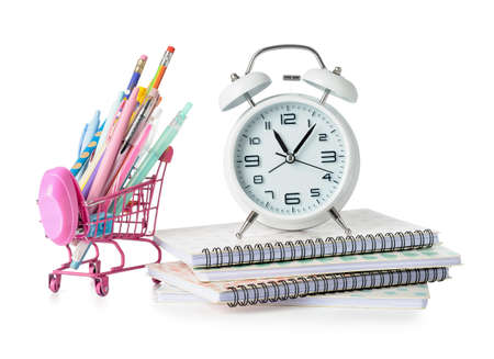 Shopping cart, alarm clock and stationery on white background