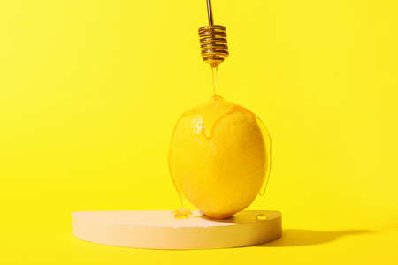 Pouring of sweet honey onto ripe lemon on color background, closeupの写真素材